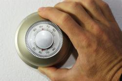 a hand adjusting the thermostat